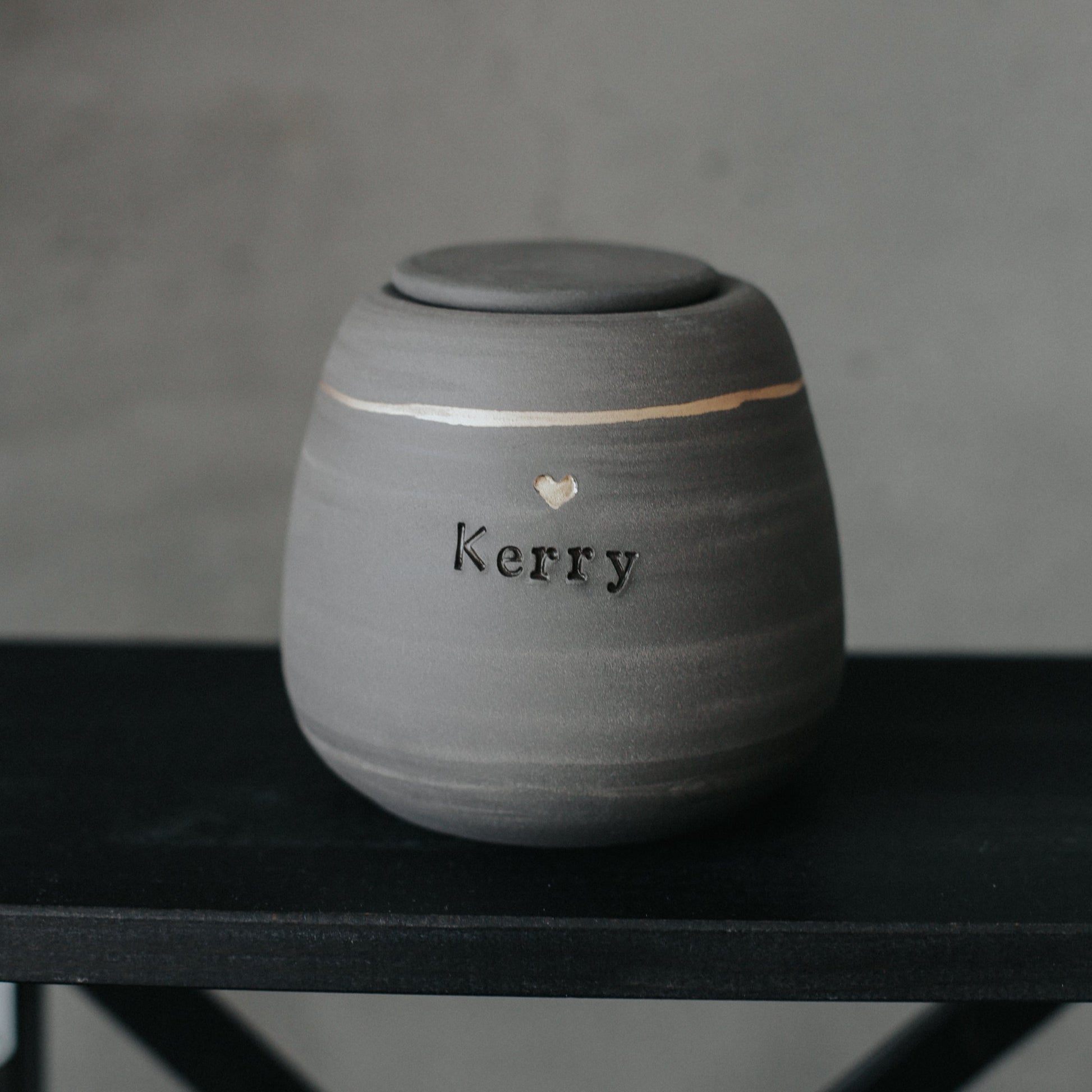 Handcrafted gray stoneware dog urn with gold heart stamp - personalized with dog's name.