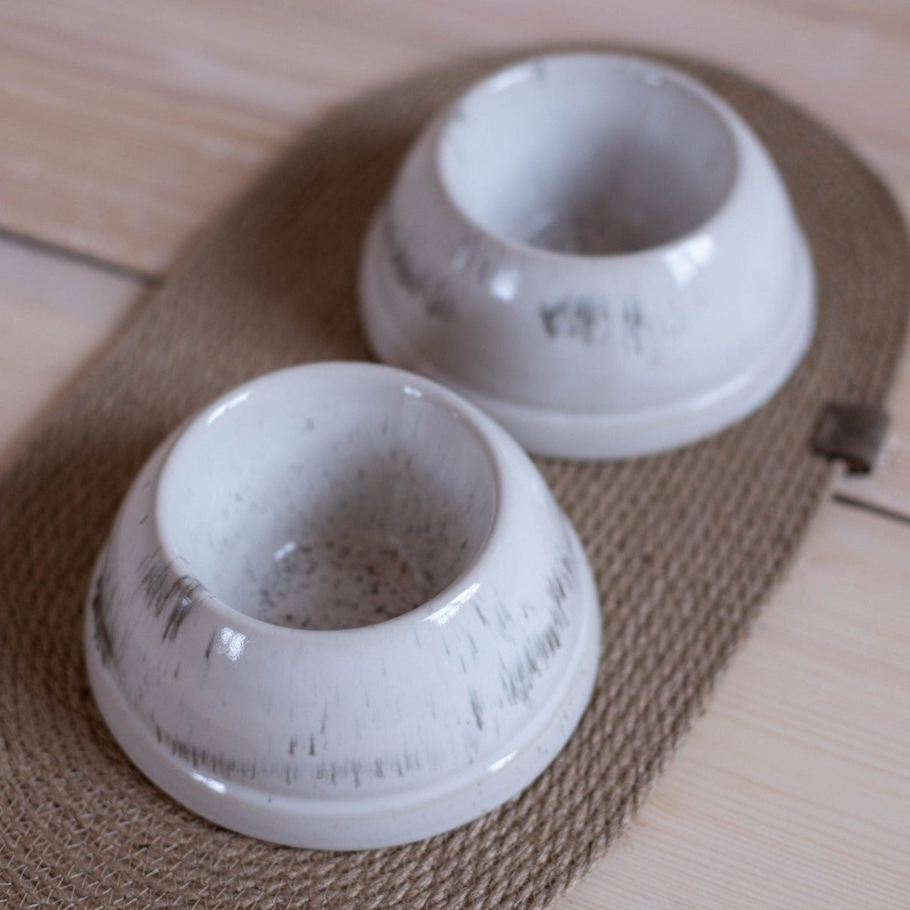 Handcrafted white ceramic dog bowls with jute mat for spaniels. Set includes 2 medium-sized bowls with a speckled glaze. 